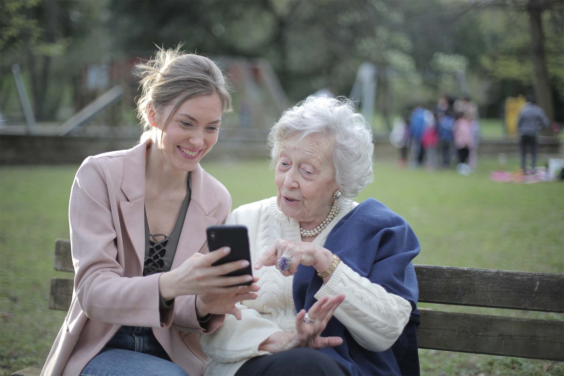 resident-and-family-member-sat-on-a-bench-looking-at-a-phone