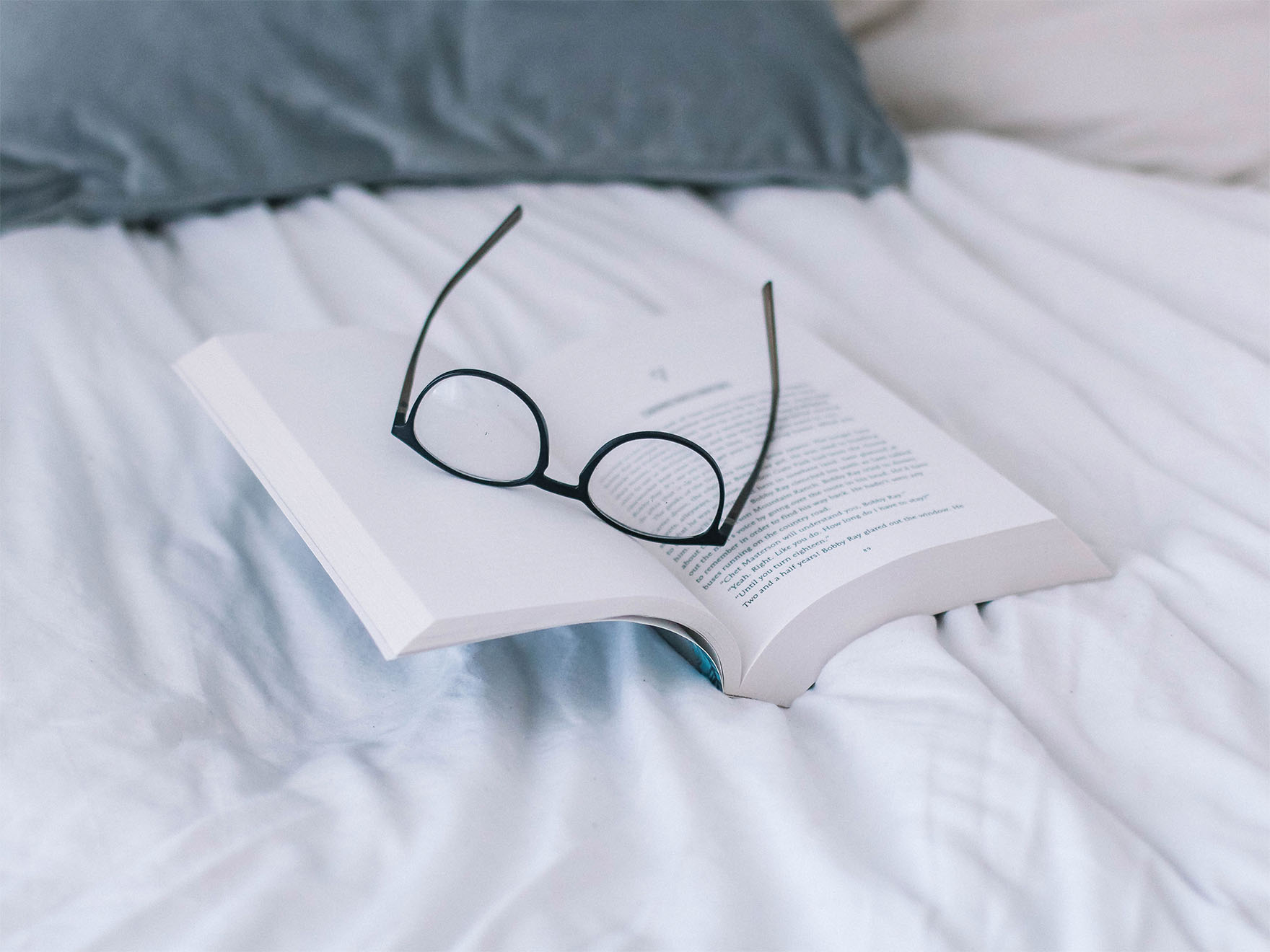 pair-of-glasses-on-book-on-a-bed