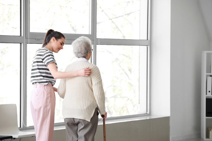 carer and a resident walking in a corridor with a walking aid