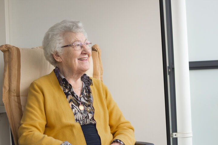 older woman sat in a seat smiling