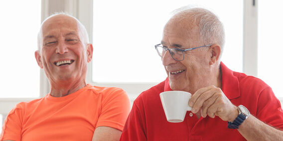 two men laughing together over a a coffee