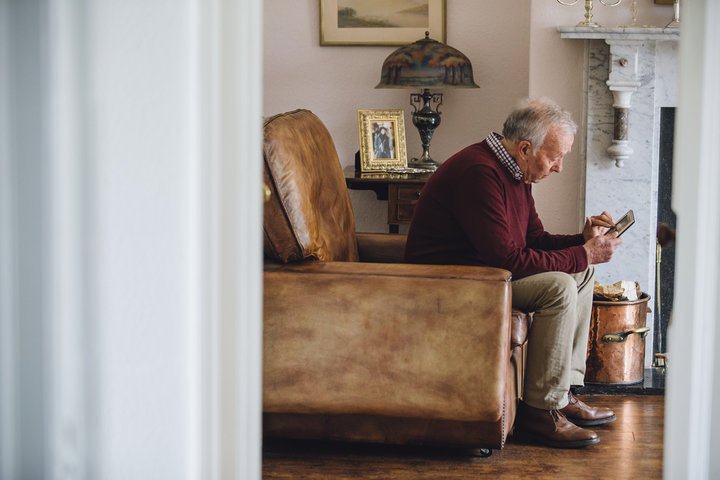 old man looking at a photo looking lonely in his livingroom
