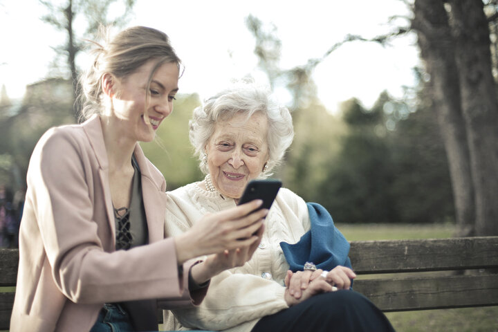 adult granddaughter showing gran a care home on her phone